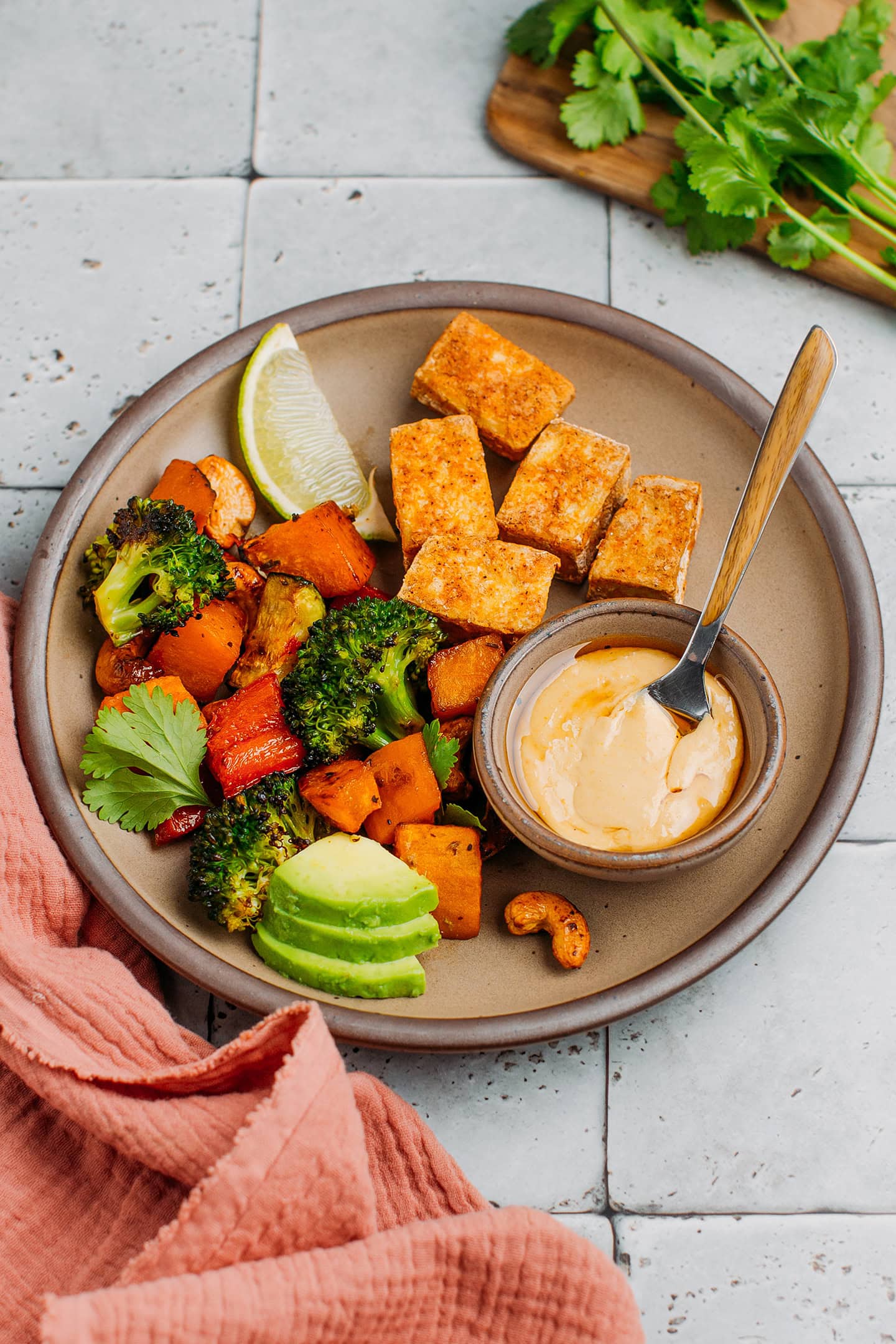 Plate filled with roasted vegetables, baked tofu, and hummus.