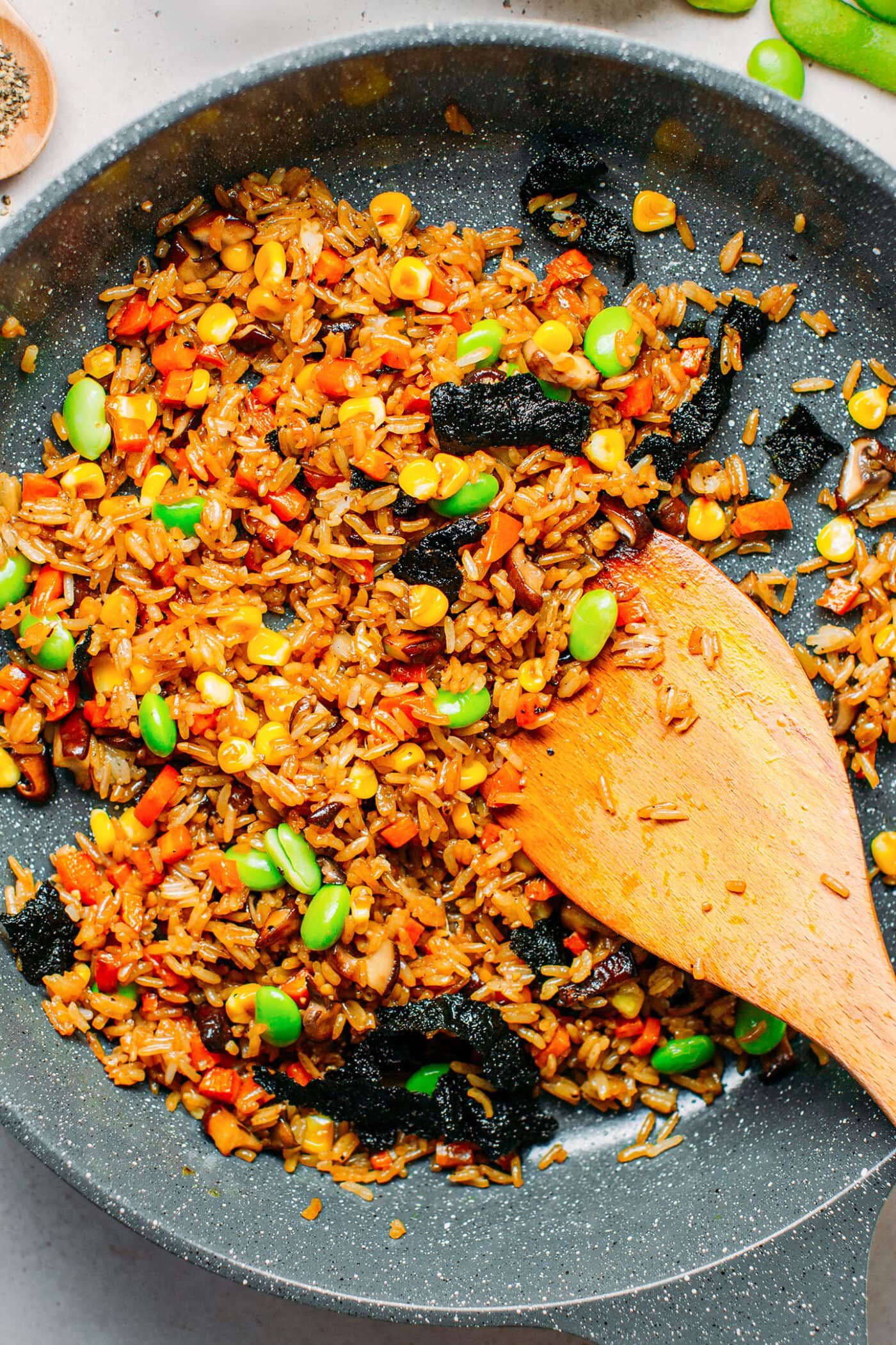 Stir-frying rice with vegetables in a skillet.