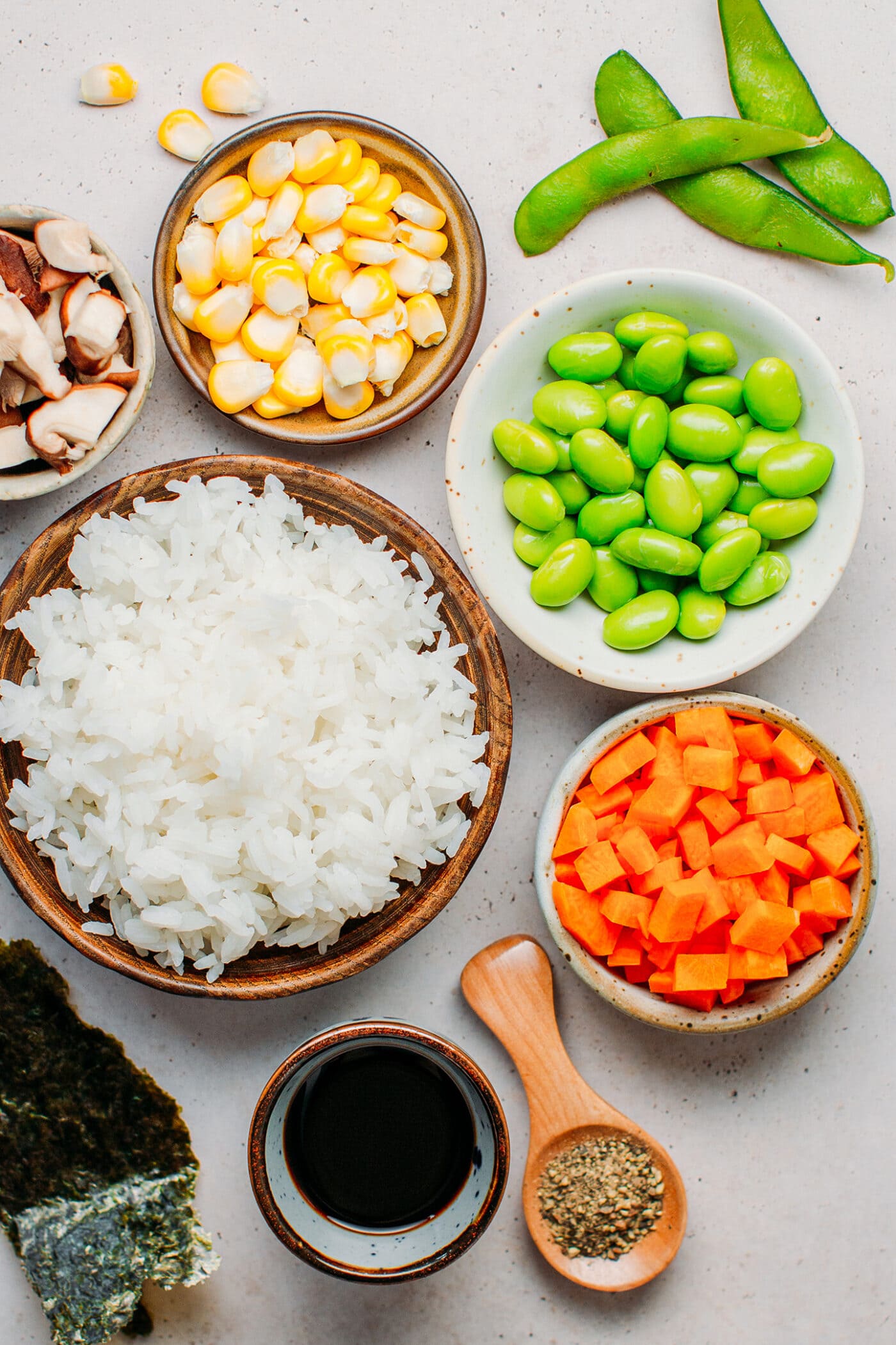 Ingredients like cooked rice, edamame, carrots, mushrooms, and corn.