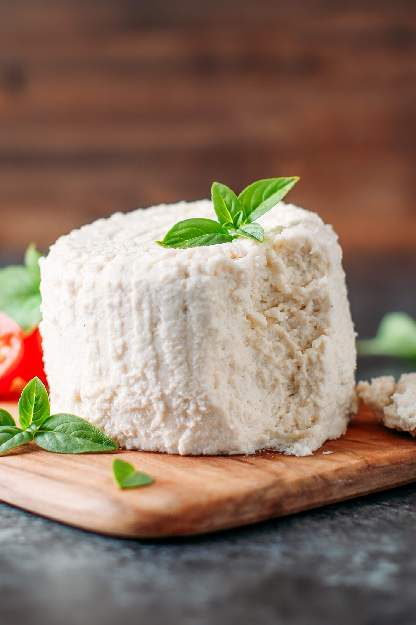 Vegan ricotta on a wooden board with fresh basil.