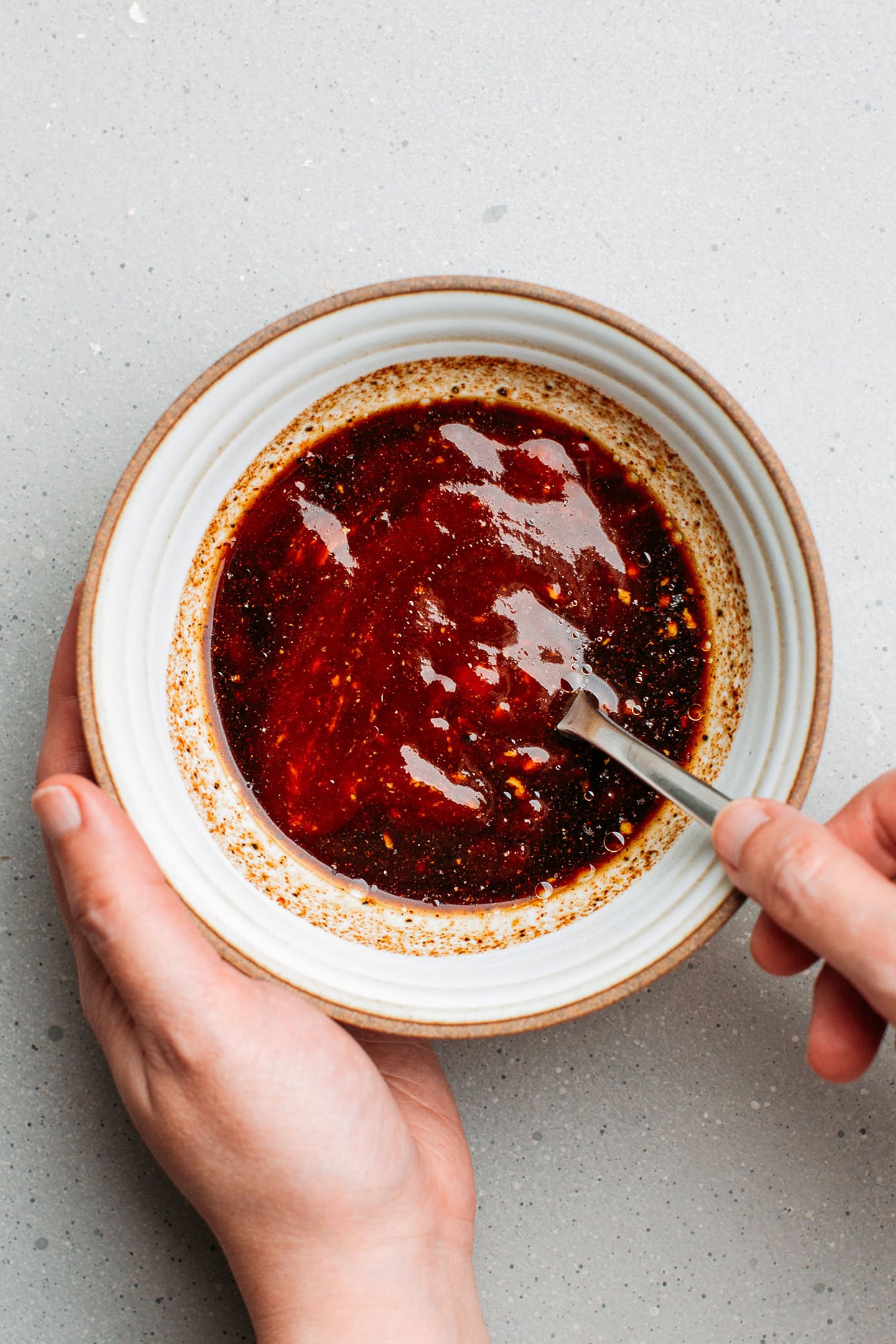 Whisking barbecue sauce in a small bowl.