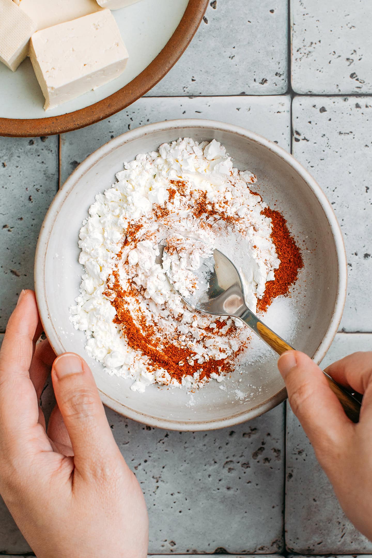 Stirring cornstarch with chili powder in a small bowl.